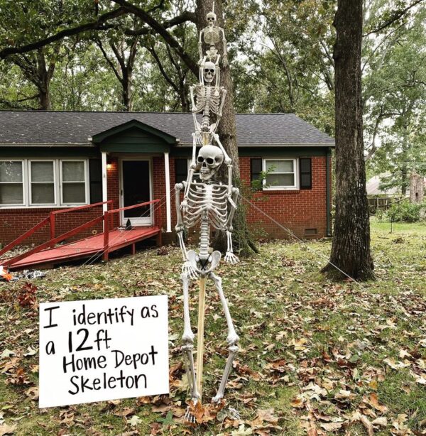 Three skeletons and a board outside a house