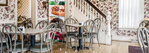 A dining room with tables and chairs and a staircase.