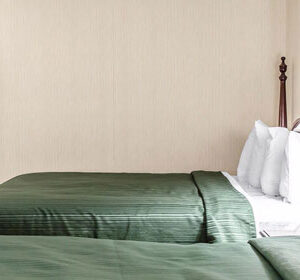 Two beds in a hotel room with green bedspreads.