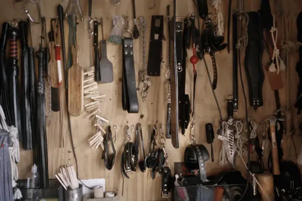 Leather and metal bondage tools on a wall.